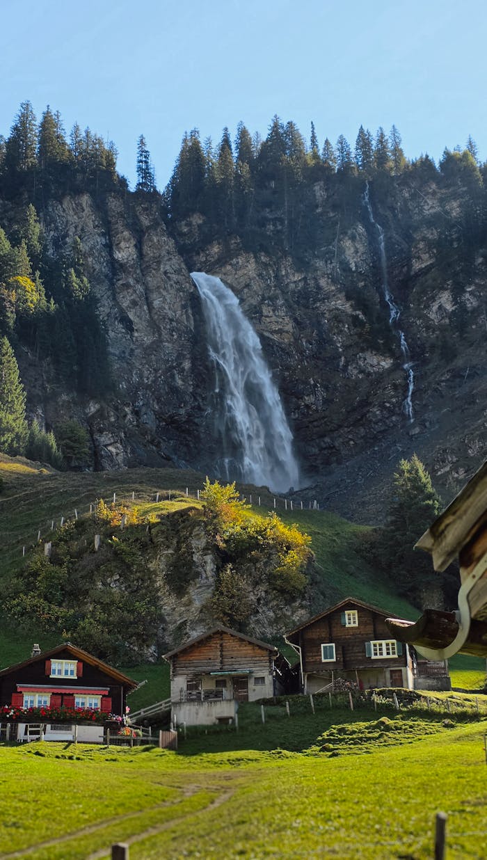About Charming Swiss chalets beneath a stunning waterfall in the Alpine village of Unterschächen.
